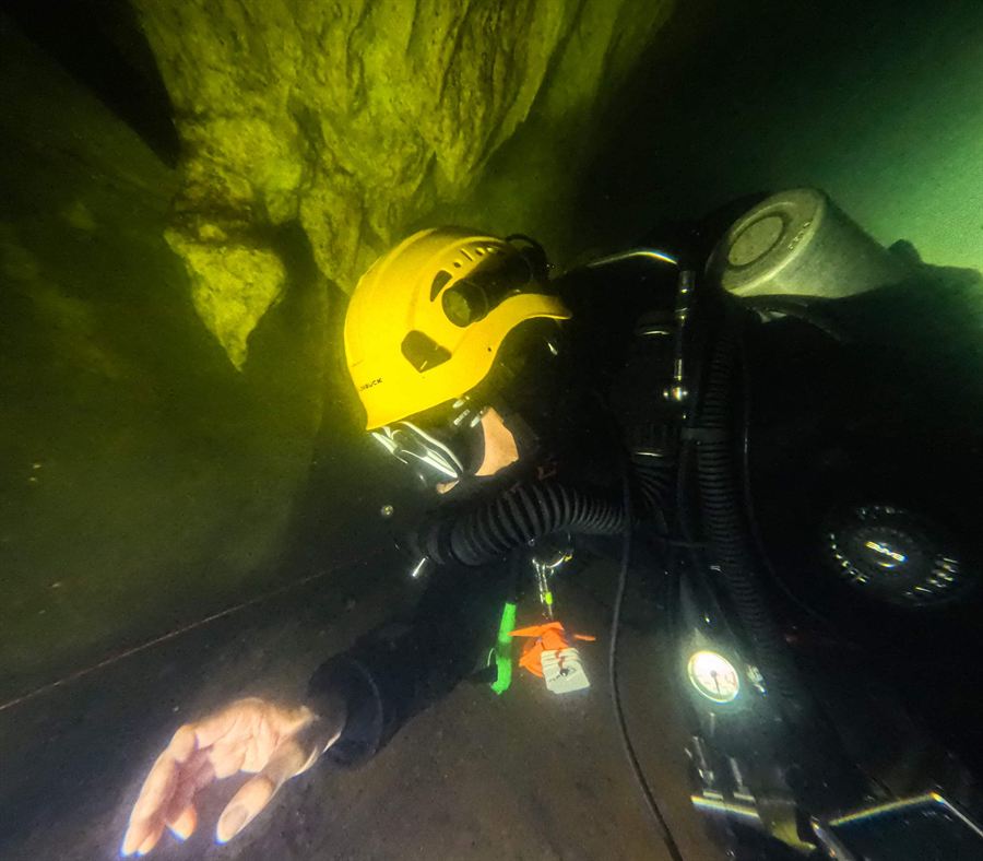 Cave dive with a helmet in greenish light